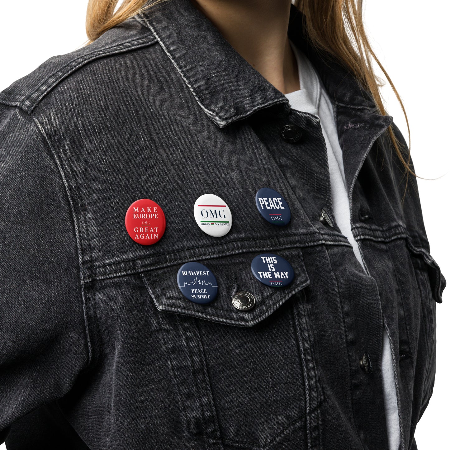 Person wearing a black denim jacket with various buttons on a white background